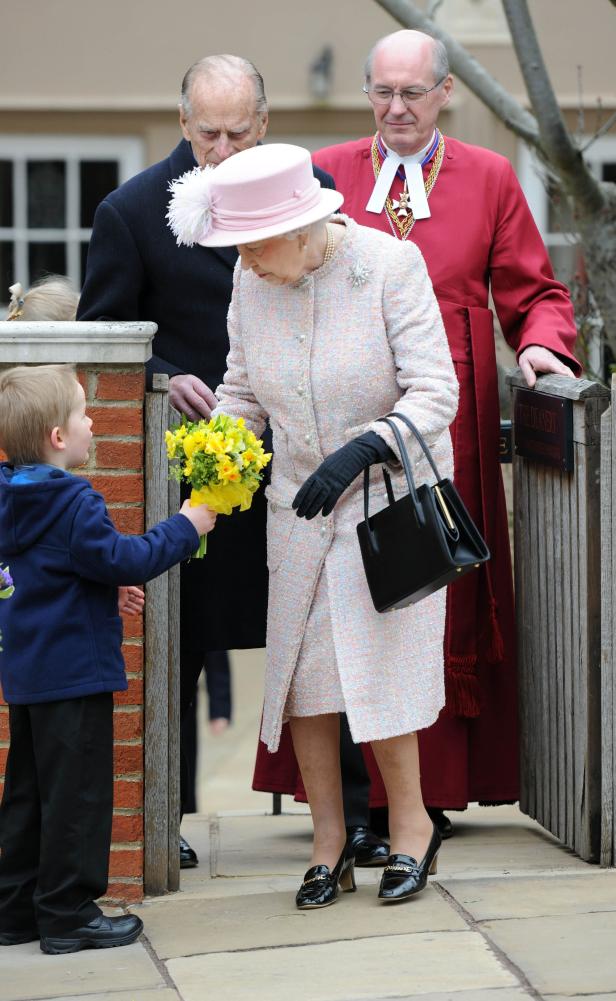 Ein Junge überreicht Königin Elisabeth II. einen gelben Blumenstrauß.