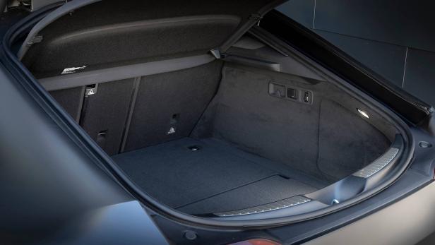 Der offene Kofferraum eines dunklen Autos mit grauer Auskleidung.