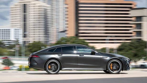 Ein grauer Mercedes-AMG GT 63 S fährt vor einer Stadtkulisse.