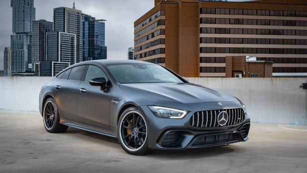 Ein grauer Mercedes-AMG GT 63 S steht vor einer Stadtkulisse.