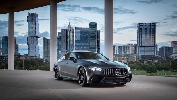 Ein grauer Mercedes-AMG GT steht vor der Skyline einer Stadt.