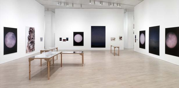 Eine Ausstellungsgalerie mit Fotografien von Himmelskörpern und Naturmotiven.