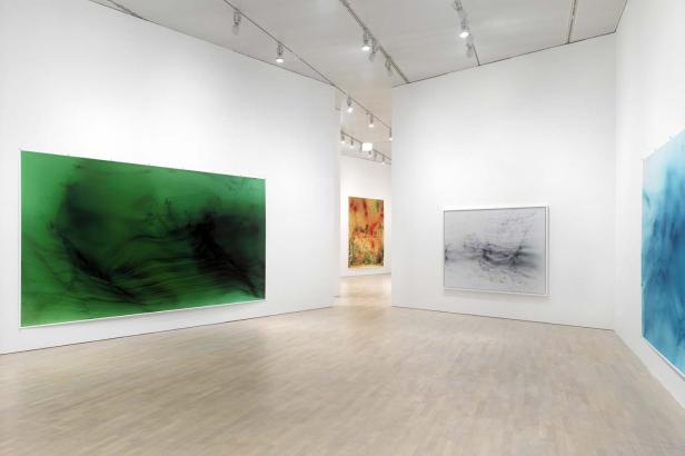 In einer Kunstgalerie hängen mehrere abstrakte Gemälde an den weißen Wänden.