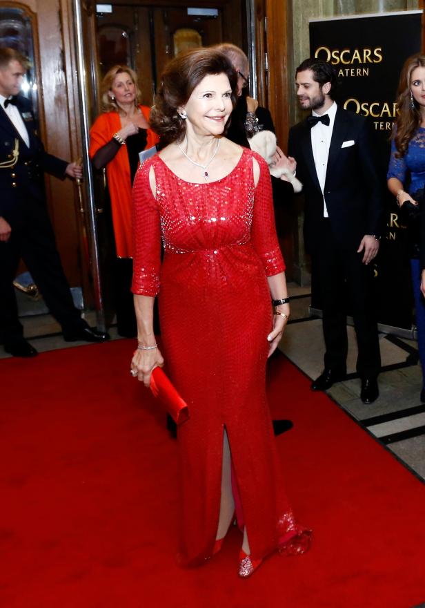 Königin Silvia von Schweden auf dem roten Teppich in einem roten Kleid.
