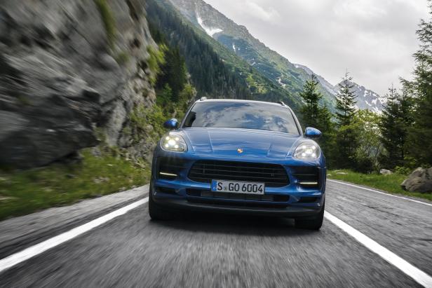Ein blauer Porsche Macan fährt auf einer Bergstraße.