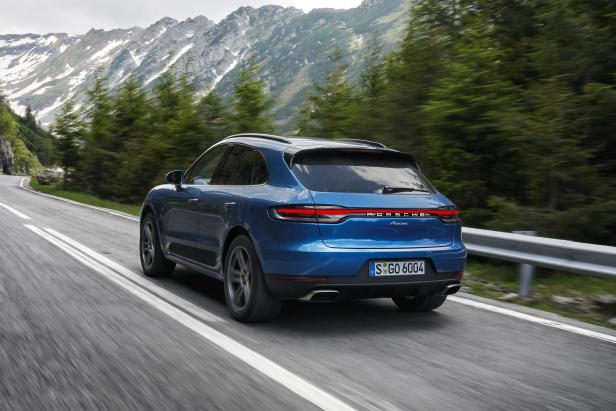 Ein blauer Porsche Macan fährt auf einer kurvigen Bergstraße.