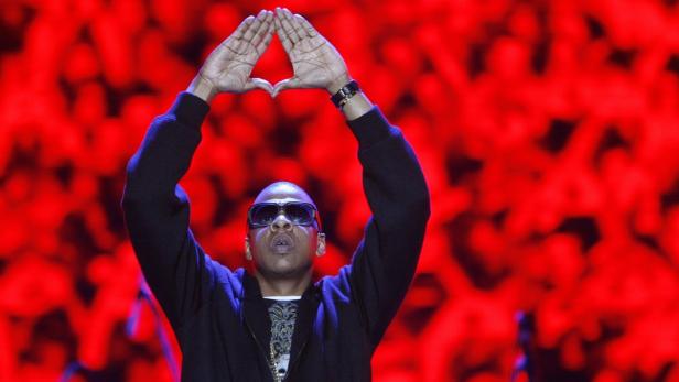 Jay-Z formt mit seinen Händen eine Raute vor einem roten Hintergrund.