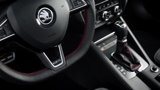 Detailaufnahme des Lenkrads und des Schaltknaufs eines Škoda VRS mit roten Ziernähten.