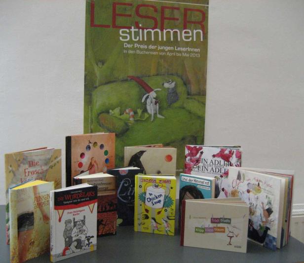 Eine Auswahl von Kinderbüchern vor einem Plakat für „Leserstimmen“.