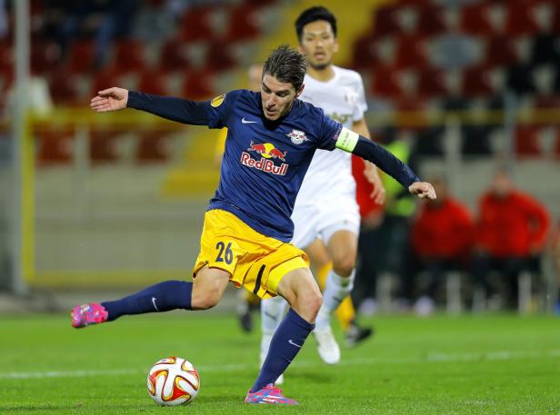 Ein Fußballspieler im Trikot von Red Bull schießt einen Ball.