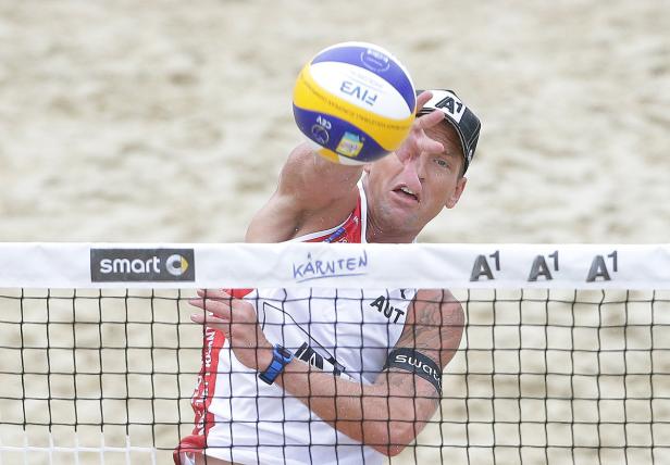 Ein Beachvolleyballspieler schlägt den Ball über das Netz.