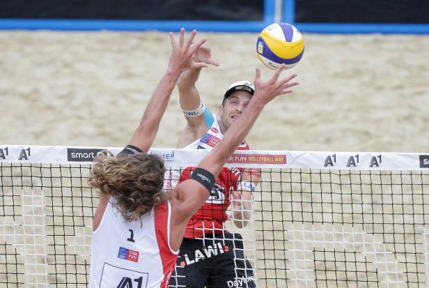 Zwei Beachvolleyballspieler blocken einen Ball am Netz.