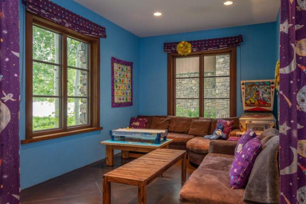 Ein Spielzimmer mit blauen Wänden, einer braunen Couch und einem Airhockey-Tisch.