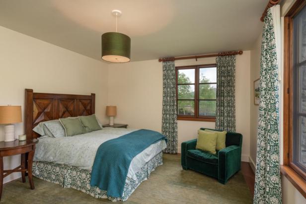 Ein Schlafzimmer mit einem Bett, einem Sessel und einem Fenster mit Blick ins Grüne.