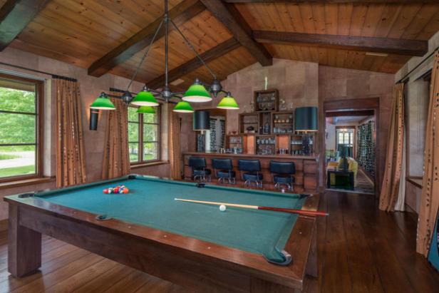 Ein Billardtisch steht in einem Raum mit einer Bar und Holzvertäfelung.