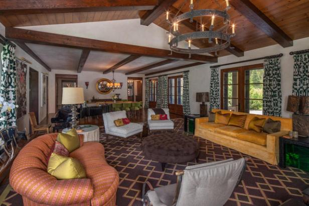 Ein Wohnzimmer mit Holzbalkendecke, verschiedenen Sitzmöbeln und einem großen Kronleuchter.