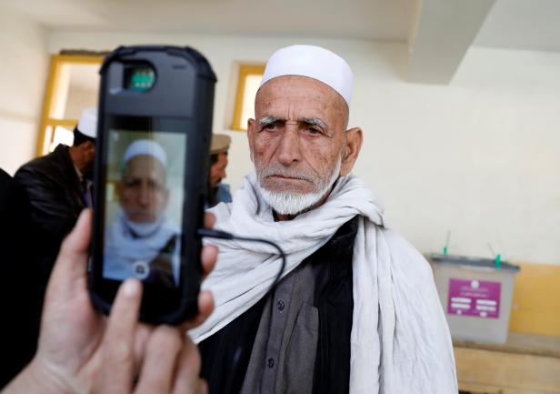 An election official scans a voter's eye with a biometric device at a polling station during a parliamentary election in Kabul