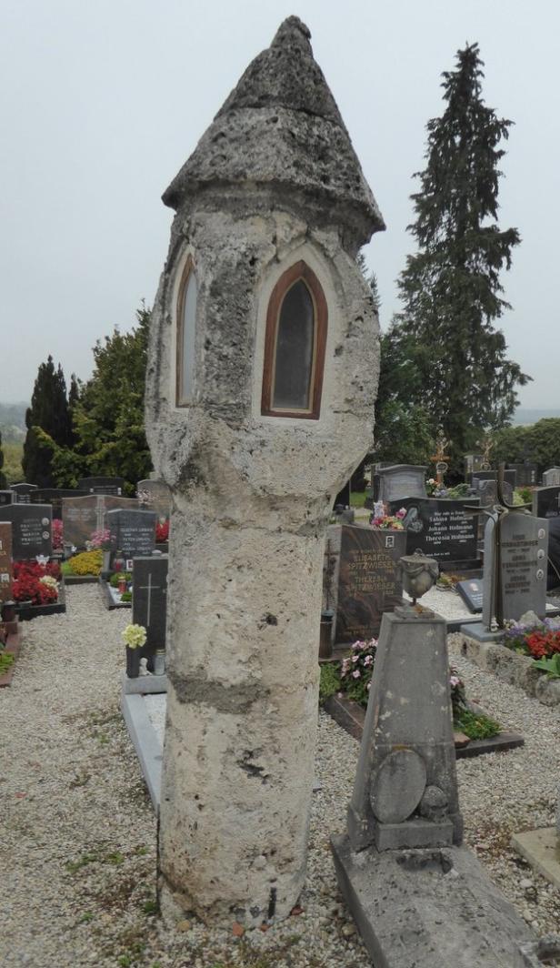 Ein gemauerter Bildstock auf einem Friedhof.