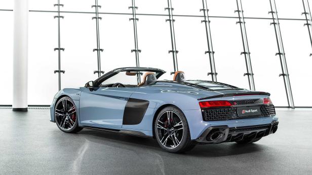 Ein blauer Audi R8 Spyder steht vor einer Glaswand.