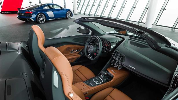 Innenansicht eines Audi R8 Spyder mit braunen Ledersitzen; im Hintergrund ein blaues Coupé.