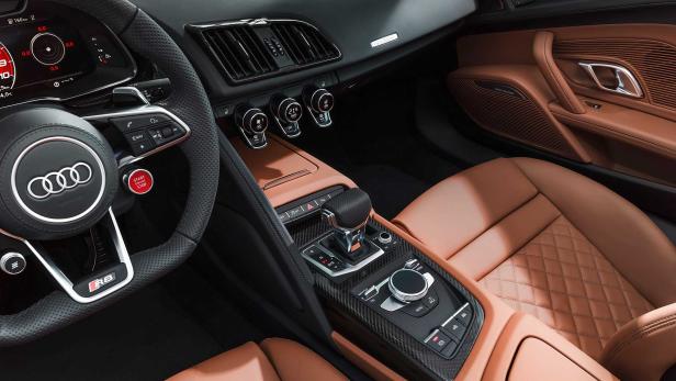 Innenraum eines Audi R8 mit braunen Ledersitzen und Karbonfaser-Akzenten.