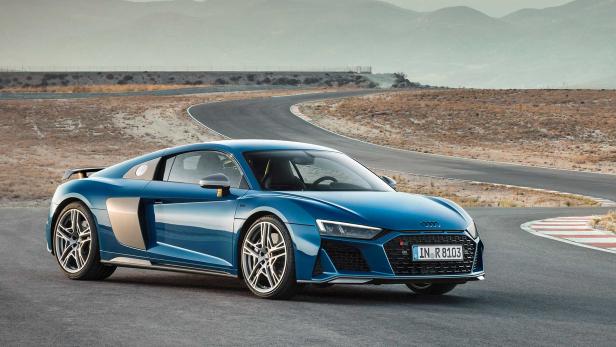 Ein blauer Audi R8 steht auf einer Rennstrecke vor einer hügeligen Landschaft.