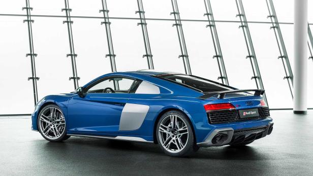 Ein blauer Audi R8 Sport steht vor einer Glaswand.