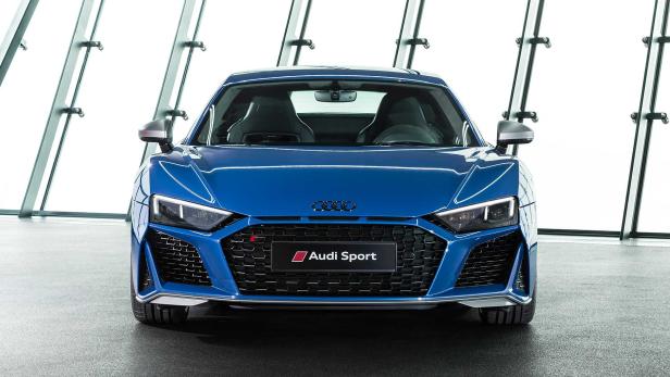 Ein blauer Audi R8 Sport steht vor einer Glaswand.