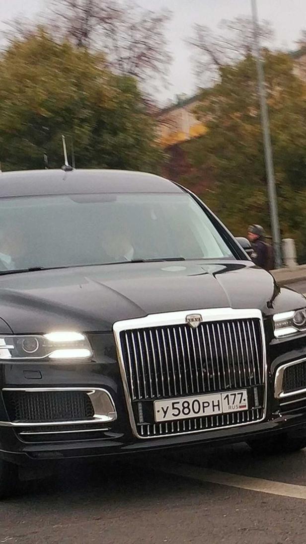 Eine schwarze Aurus Limousine fährt auf einer Straße.