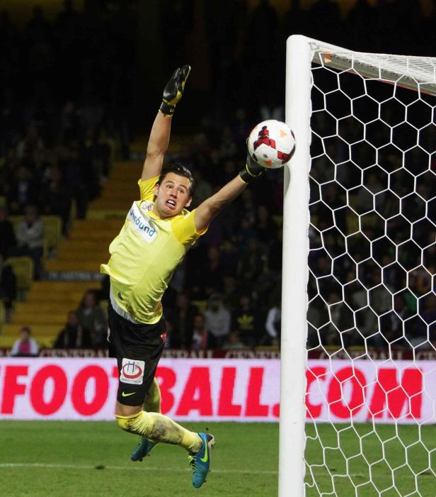 Ein Torwart springt, um einen Fußball vor dem Tor abzuwehren.