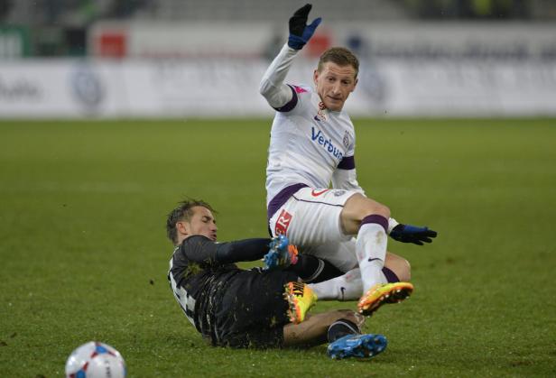 Zwei Fußballspieler kämpfen auf dem Rasen um den Ball.