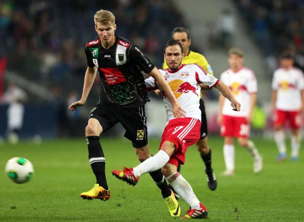 Zwei Fußballspieler kämpfen um den Ball auf dem Spielfeld.
