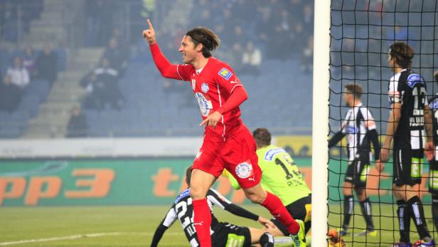 Ein Fußballspieler in roter Spielkleidung jubelt auf dem Spielfeld.
