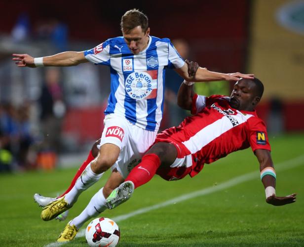 Zwei Fußballspieler kämpfen um den Ball auf dem Spielfeld.