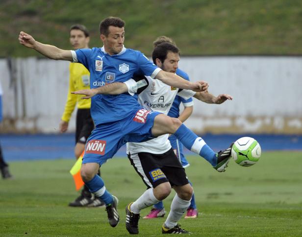 Zwei Fußballspieler kämpfen um den Ball während eines Spiels.