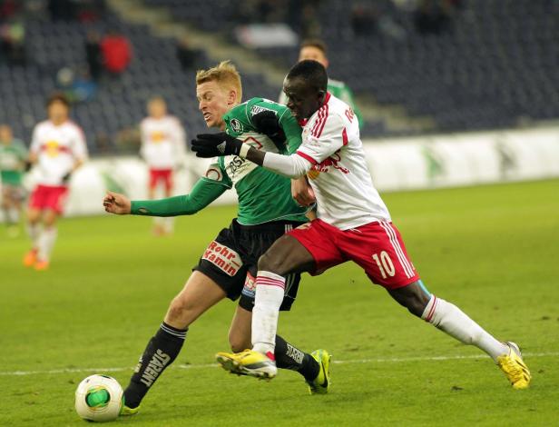 Zwei Fußballspieler kämpfen um den Ball auf dem Spielfeld.