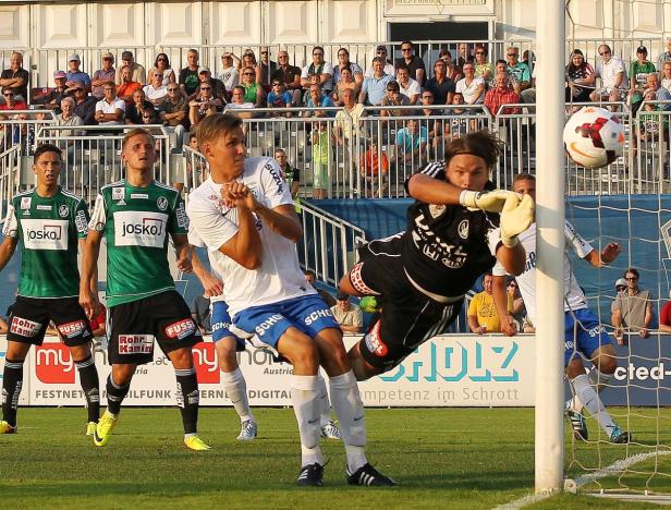 Ein Torwart springt, um einen Fußball während eines Fußballspiels zu halten.