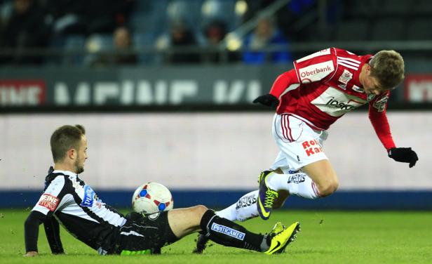 Zwei Fußballspieler kämpfen um den Ball auf dem Spielfeld.