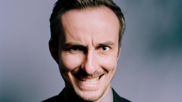 NEO MAGAZIN mit Jan Böhmermann Ein Mann mit Anzug und einem verschmitzten Lächeln blickt in die Kamera.