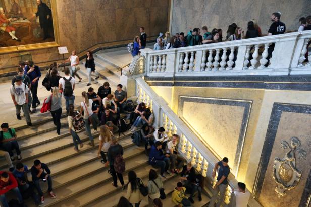 Eine Gruppe von Menschen sitzt und steht auf einer Treppe in einem Gebäude.