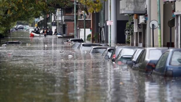 Eine überflutete Straße mit Autos und einem Rettungsboot.