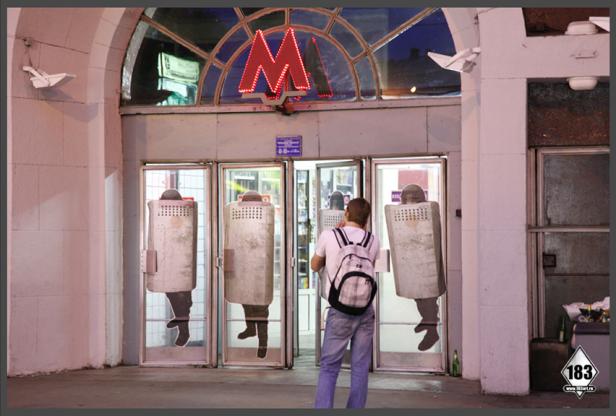 Ein Mann steht vor dem Eingang einer Metrostation, deren Türen mit Aufklebern von Polizisten mit Schutzschilden versehen sind.