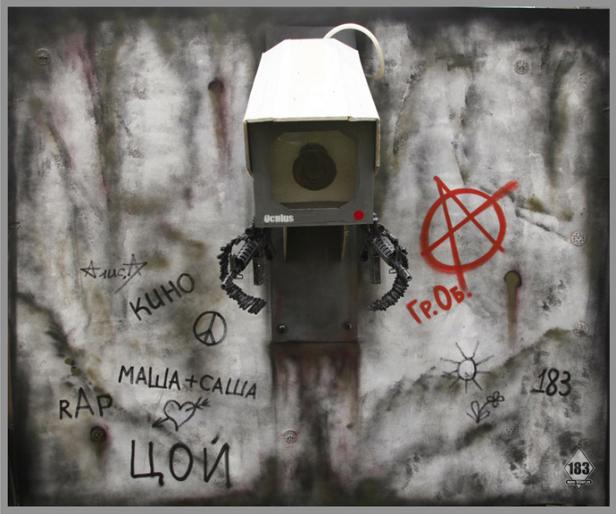 Eine Überwachungskamera vor einer Wand mit Graffiti und russischen Schriftzeichen.