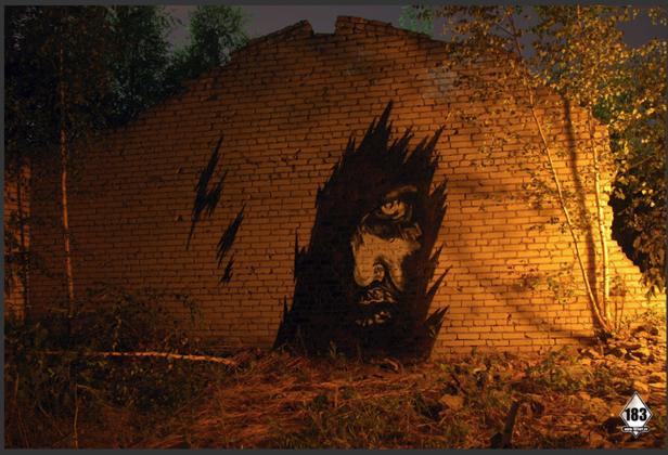 Ein Graffiti mit einem Gesicht an einer alten Backsteinmauer.