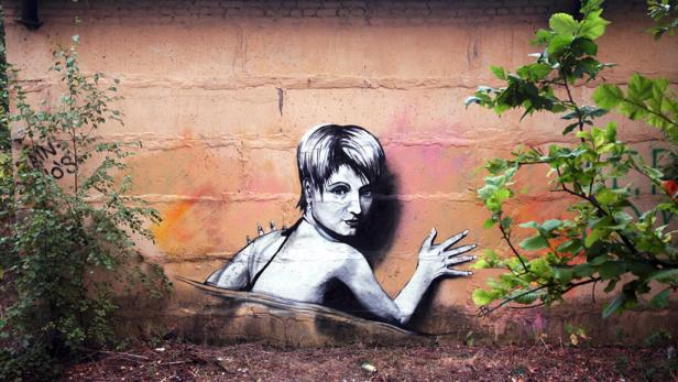Ein Graffito an einer Wand zeigt eine Frau, die aus dem Wasser aufzutauchen scheint.