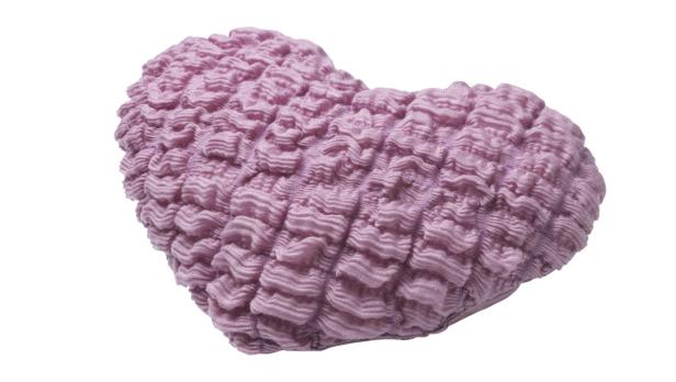 Ein herzförmiges Kissen mit einer gerafften, lavendelfarbenen Textur.