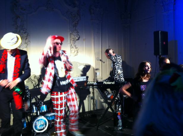 Eine Band tritt mit Keyboards und Schlagzeug auf einer Bühne auf.