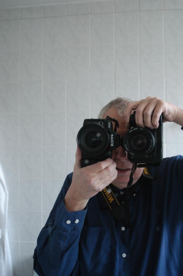 Ein Mann macht ein Spiegel-Selfie mit zwei Nikon-Kameras.