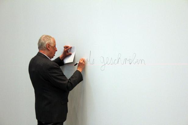 Ein Mann schreibt mit einem Stift auf eine weiße Wand.
