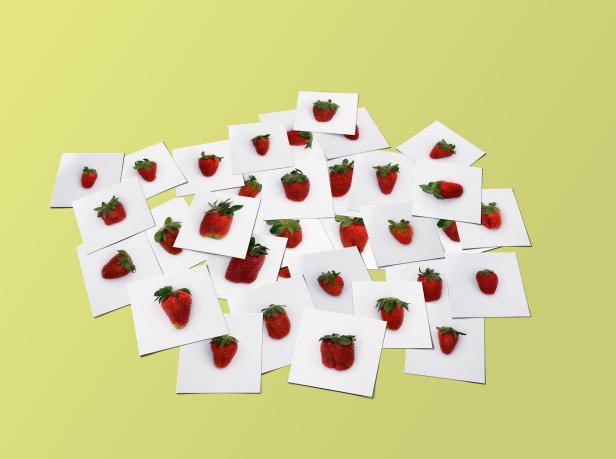 Viele Erdbeeren liegen auf kleinen, weißen Karten auf einem gelben Hintergrund.